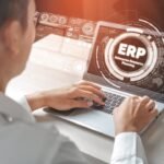 Profissional mexendo no computador enquanto realiza a implementação de um ERP.