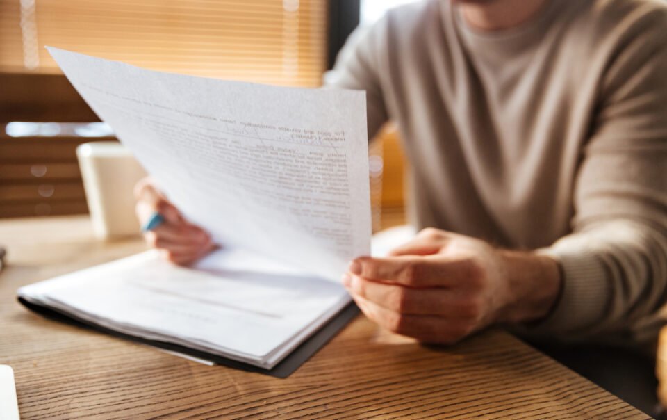 Homem de negócios lendo documento em papel e entendendo a qual a diferença entre ecf e ecd.