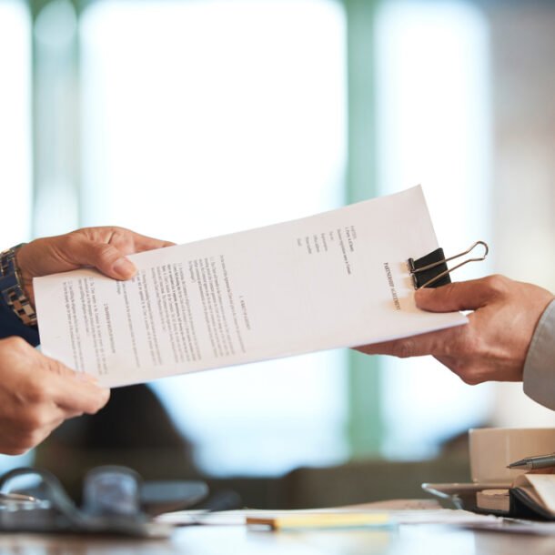 Profissionais em um escritório passando um documento entre si que representa o pedido de venda.