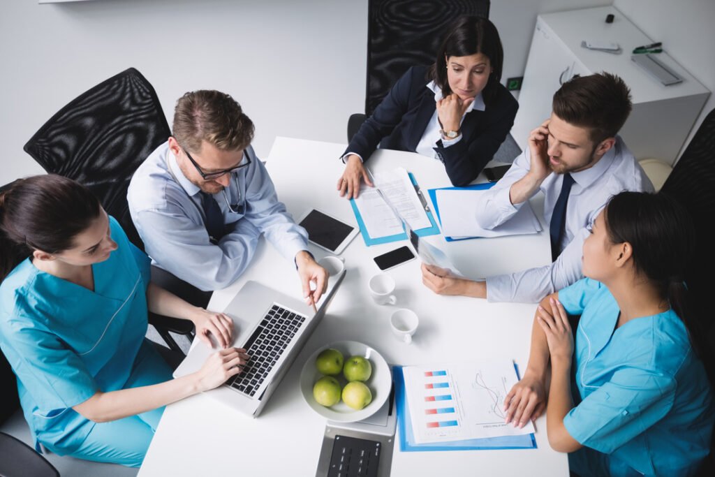 Profisisonais da saúde reunidos em uma mesa discutindo a gestão de planos de saúde.