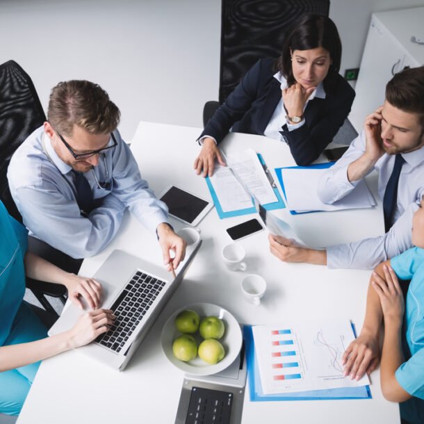 Profisisonais da saúde reunidos em uma mesa discutindo a gestão de planos de saúde.